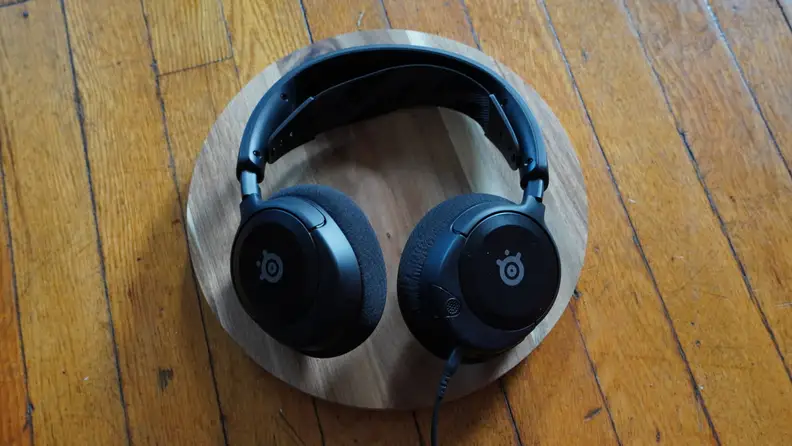 A pair of black SteelSeries headphones lays on a surface.