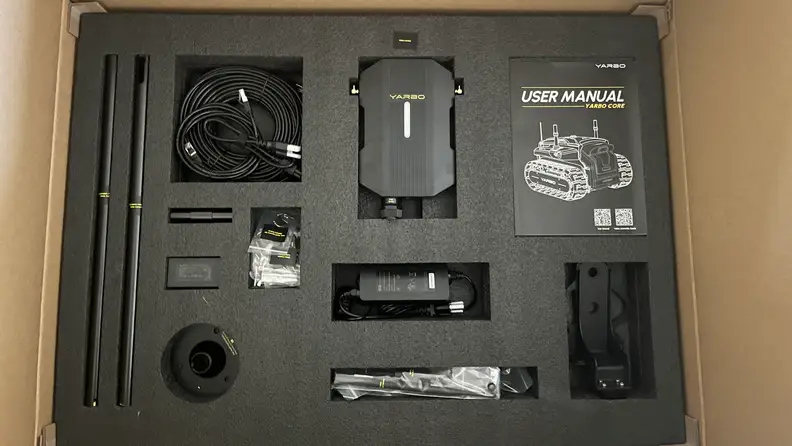 Black interior of Yarbo Core Robot Lawn Mower box showing various parts unassembled.