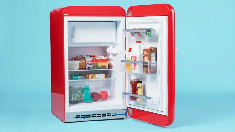 A close up of the Smeg FAB10URRD3 mini fridge. Its door is open, showcasing a fully-stocked interior.