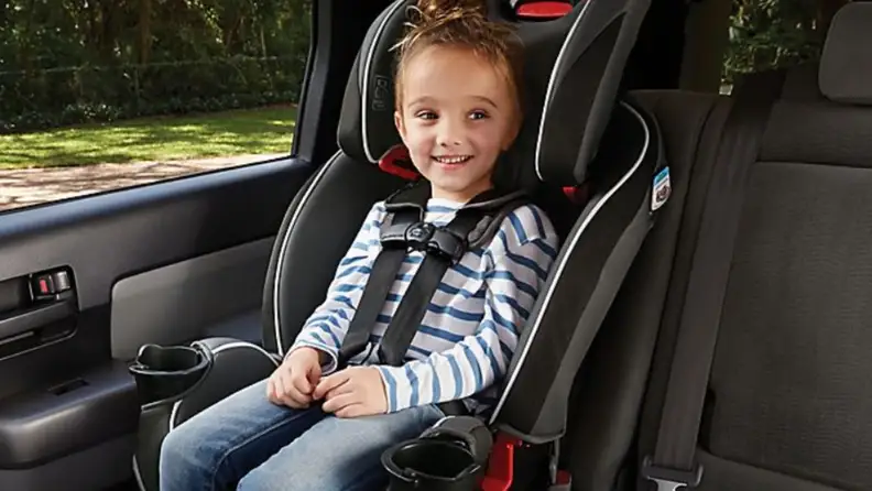 A child sits smiling in their Graco car seat.
