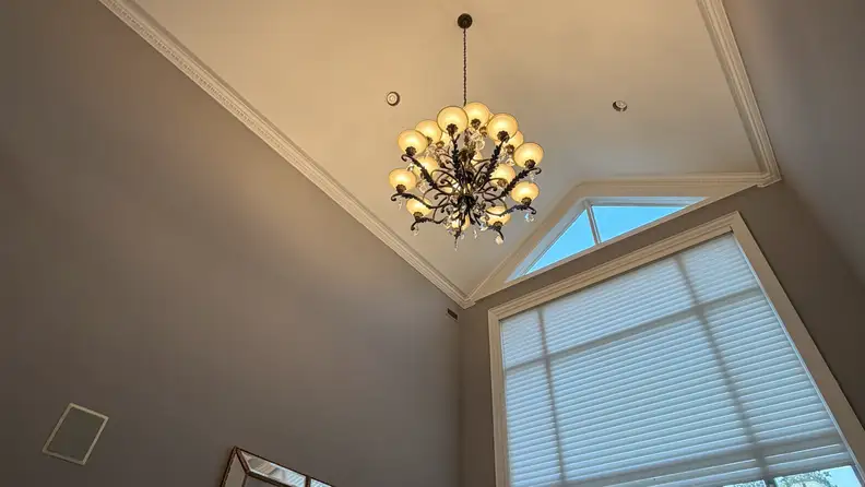 Chandelier hanging from ceiling surrounded by grey walls.