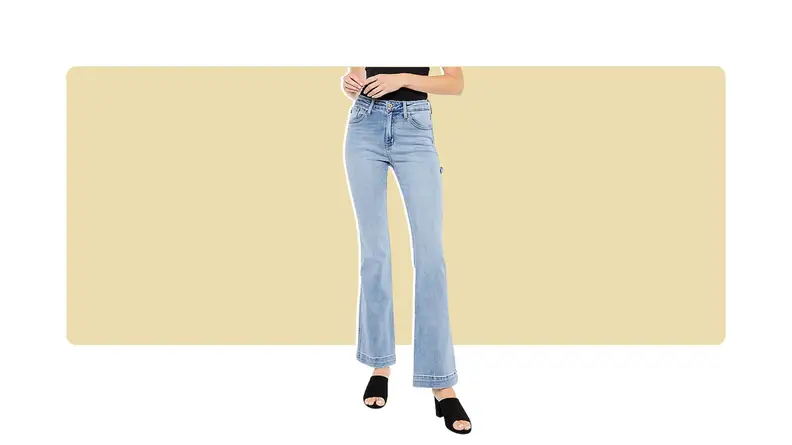 A model wearing light-wash bootcut jeans with black slip on shoes.