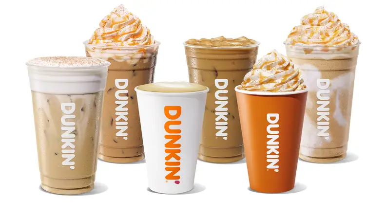 Lineup of iced and hot coffee cups topped with whipped cream