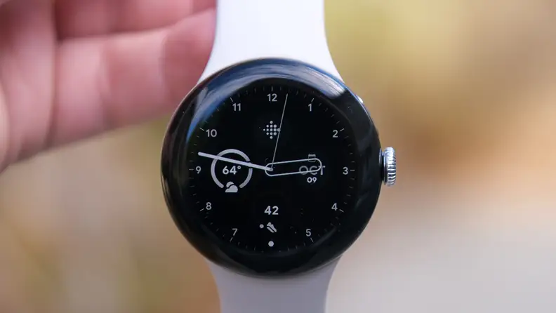 Our reviewer holds the Pixel Watch 2 by its white strap, showing off the watch's face.
