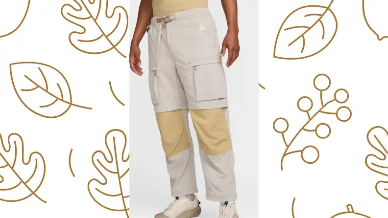 A person stands in a pair of pants from the waist down, over a leaf-printed background
