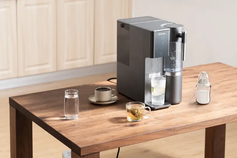 Black Waterdrop A2 reverse Osmosis system on a wooden table with cups of tea and coffee