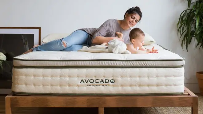 A baby and parents lay on a mattress.