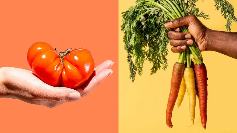 On left, person hold orange heirloom tomato in hand. On right, person holds bundle of carrots in hand by their green stalk.