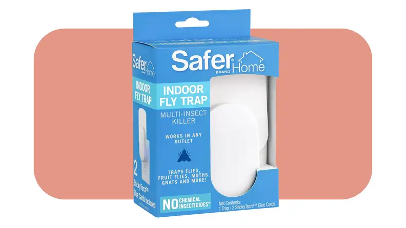 Product shot of the Safer Home Plug-in Fly Trap inside of blue box packaging in front of pink background.