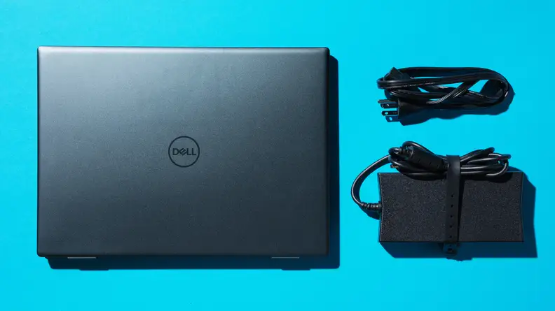 The Dell Inspiron 14 Plus on a blue background with cords wrapped up next to the laptop.