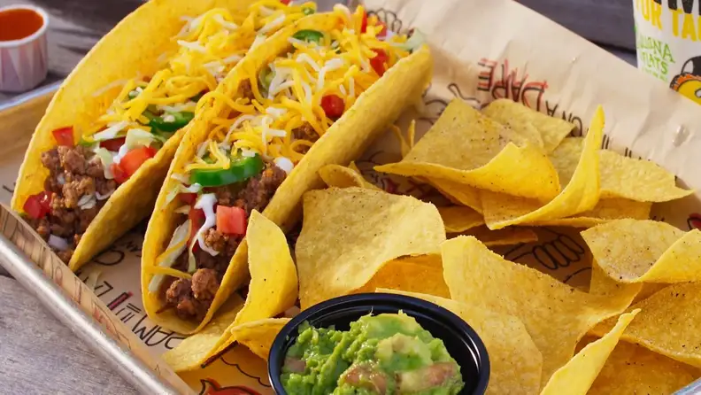 Two hard-shell tacos with chips and guacamole