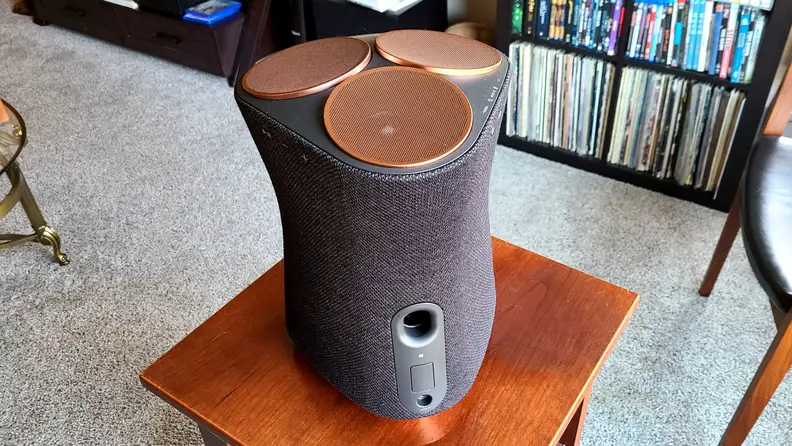 Sony SRS-RA5000 sits on a wooden table, its bass port and copper colored top drivers in view