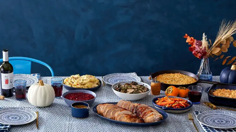 A table filled with Thanksgiving dishes, including turkey, carrots, cranberry sauce, and more.
