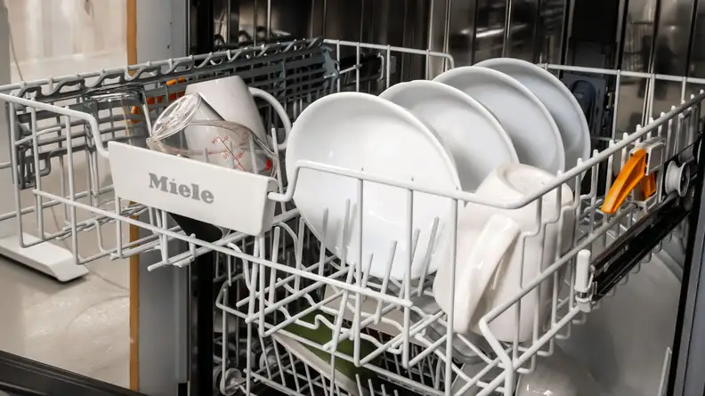 A few mugs and bowls sit in the middle rack of the dishwasher.