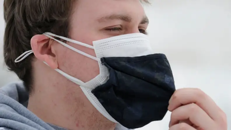 Close-up: An individual wears two cloth masks for extra protection against airborne diseases.