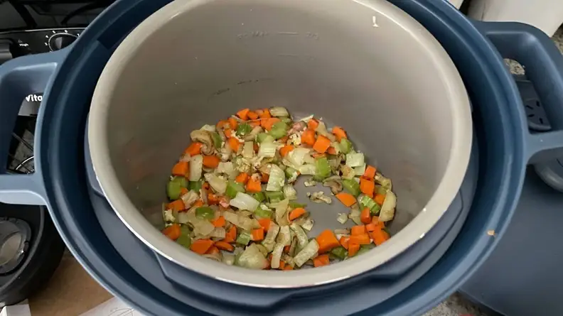 Various chopped vegetables cooking inside of the Our Place Dream Cooker.