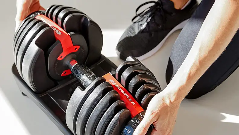 A woman adjusting the weight on the Bowflex adjustable dumbbells.