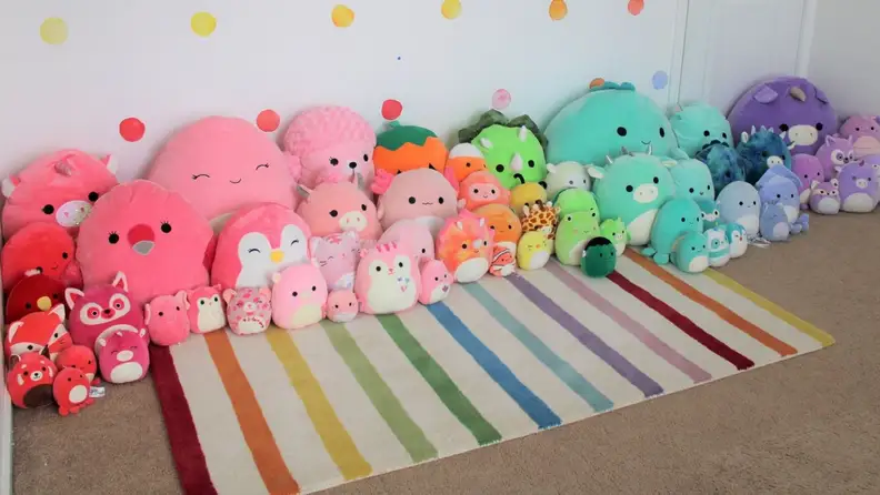 a variety of squishmallows arranged to create the colors of a rainbow