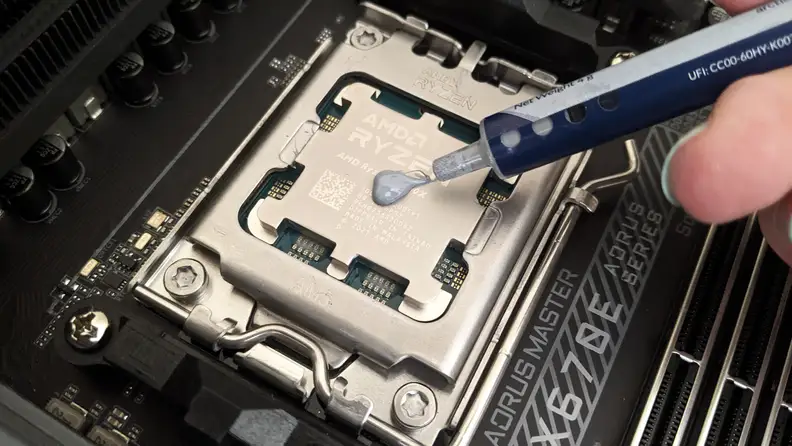 Applying a gray thermal paste onto the top of a computer processor