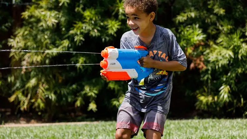 A boy shoots water from a Nerf Twin Shot Super Soaker