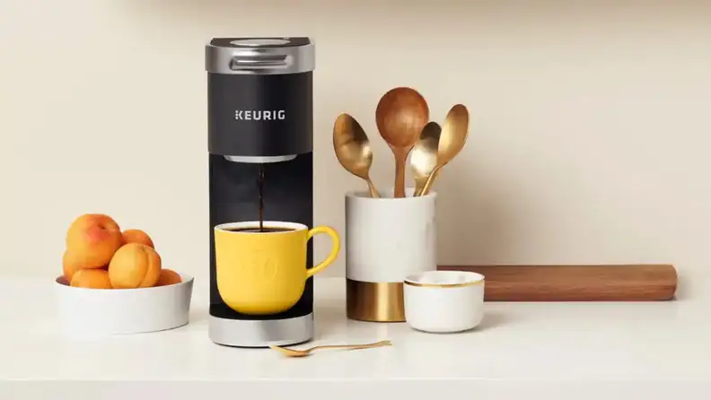 Black Keurig coffee maker brewing coffee on countertop.