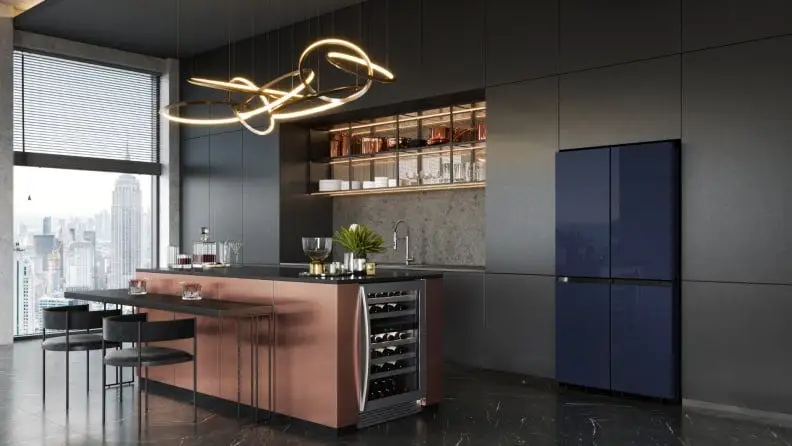 A dark kitchen with grey cabinets and dark appliances, overlooking New York City.