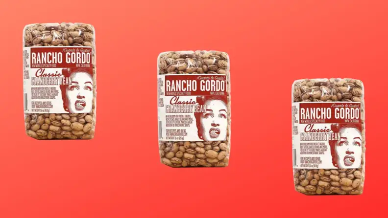 Three packages of cranberry beans arranged in a diagonal row on a red background.