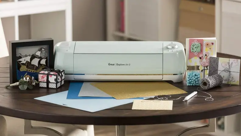 A Cricut machine sitting on a table surrounded by craft paper.