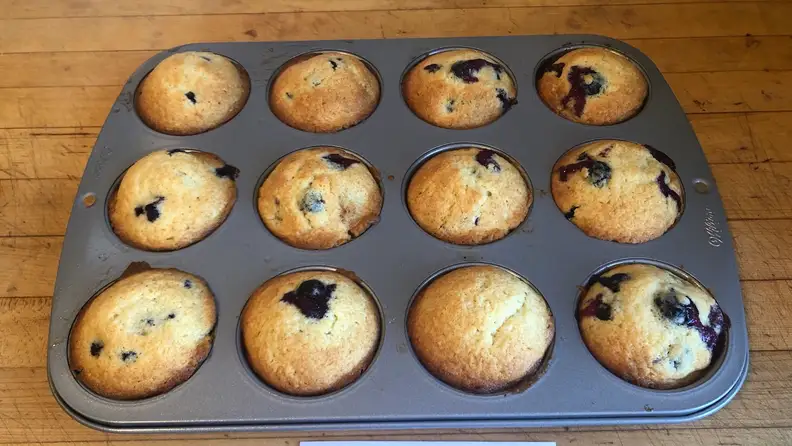 The Wilton muffin pan filled with baked muffins sitting on a counter.