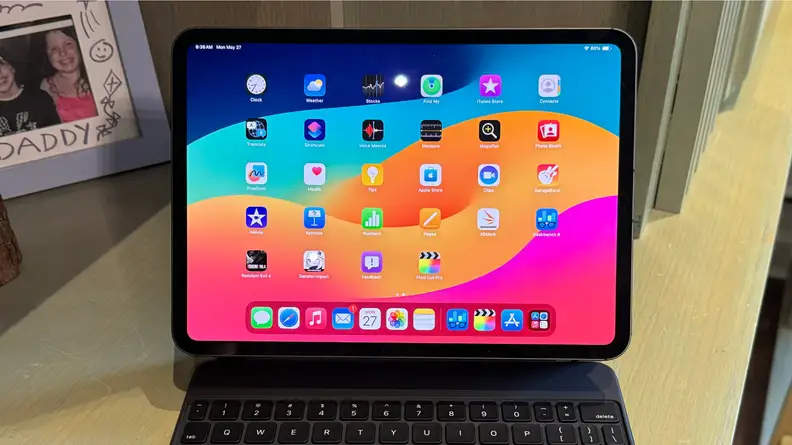 A photo of the 2024 iPad Pro attached to a Magic Keyboard. The tablet is sitting on a desk.