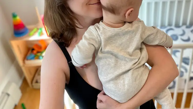 A parent holds their infant while wearing the Storq Full Cup Nursing Bra in black.