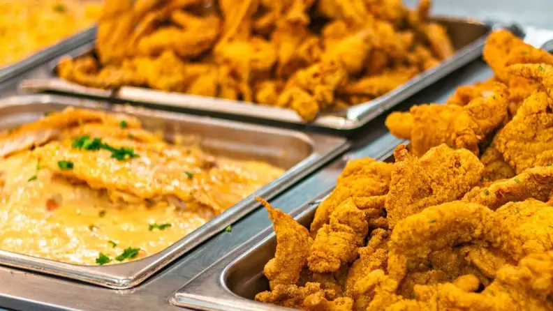 Close-up of trays with fried chicken and seafood at a hot bar