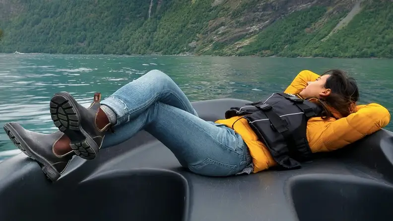 Woman lying on a boat wearing a pair of Blundstone boots.