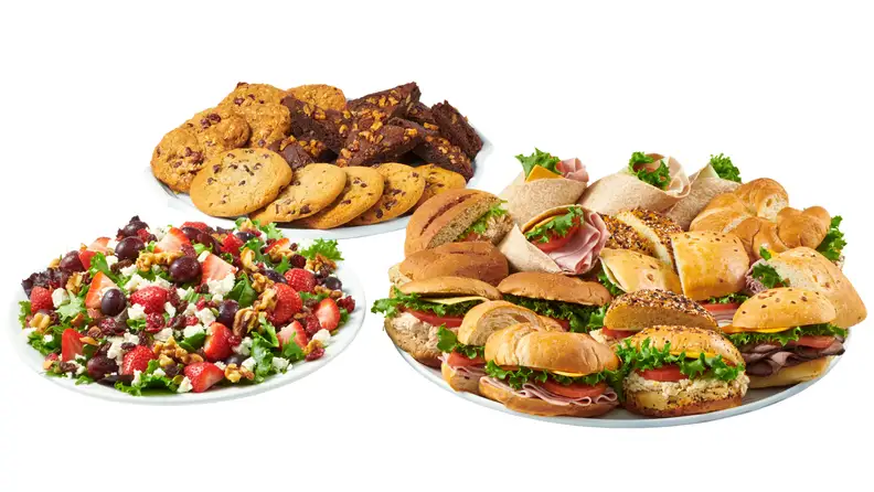Platters of sandwiches, wraps, cookies, brownies, and a fruit salad