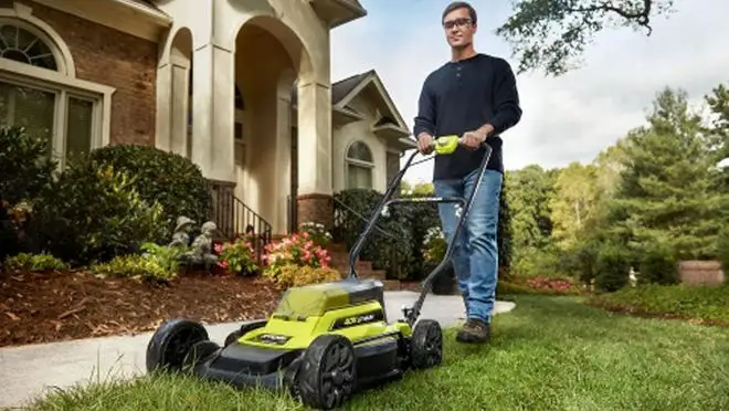 A person mows a lawn with a lawnmower.