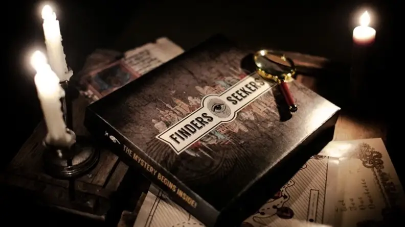 A box labeled Finders Seekers surrounded by candles and a magnifying glass