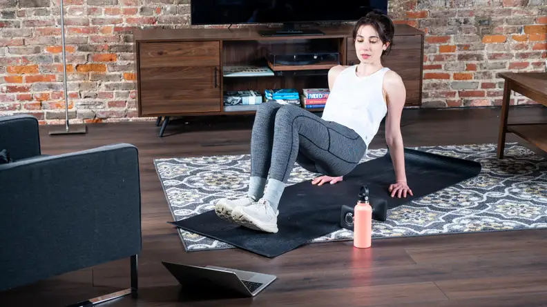 woman exercising at home in front of apple laptop