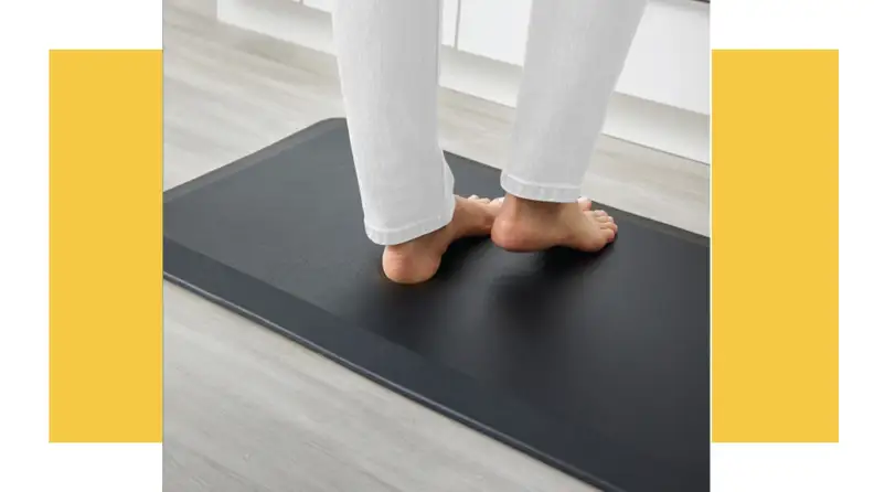 Person's feet standing on a kitchen mat
