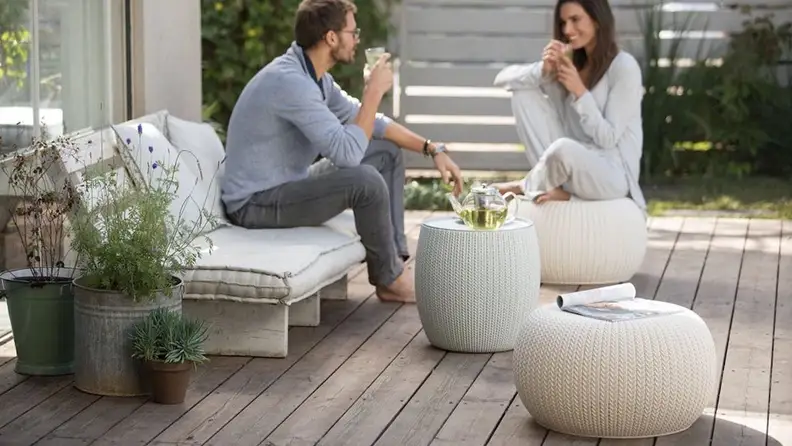 Couple sitting on cozy patio wearing pajamas and drinking tea.