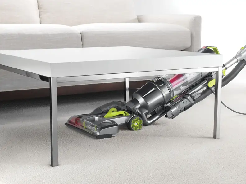 A Hoover vacuum cleans under a table