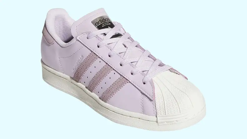 A white, adidas Superstar on a light blue background.