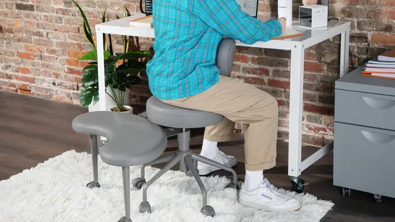 Person sitting backwards in the Pipersong Meditation Chair while working at desk on laptop computer.