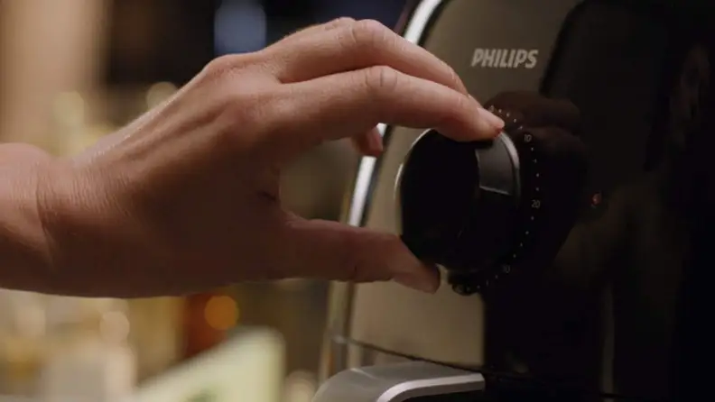 Person turning dial on black AirFryer.