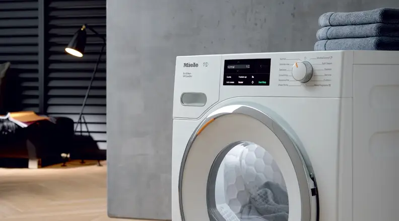 The Miele T1 compact ventless dryer appears in a room.