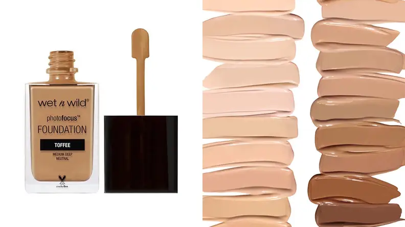On the left, the Wet n Wild PhotoFocus Liquid Foundation in a medium shade stands on a white background with the cap off to expose a spatula-like applicator. On the right, every shade of the foundation is swatched on a white background in two columns.