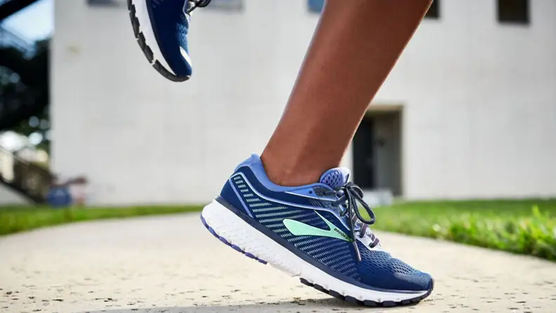 A close-up of a foot wearing Brooks Ghost 12 running shoes on pavement.