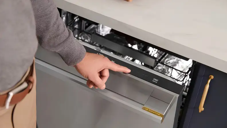 Person pressing the hidden touch controls on an open dishwasher door.