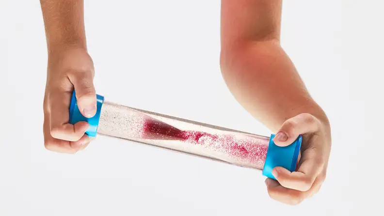 Hands tip a clear plastic tube with red liquid inside.