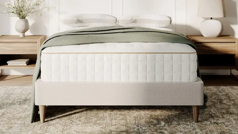 Naturepedic EOS Classic Customizable Organic Mattress in a bedroom with a tan rug in front of a white wall and nightstands with lamps.