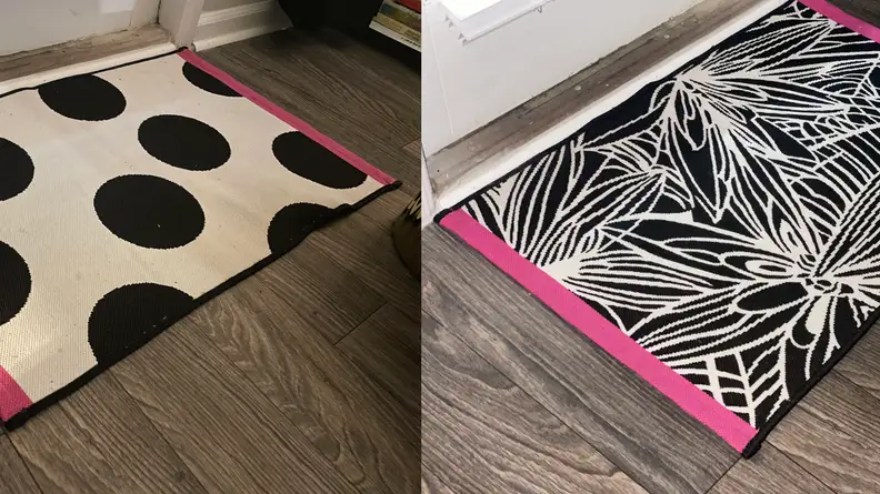 Reversible white rug with black polka dots and pink border on one side and black and white leaf pattern on the other.